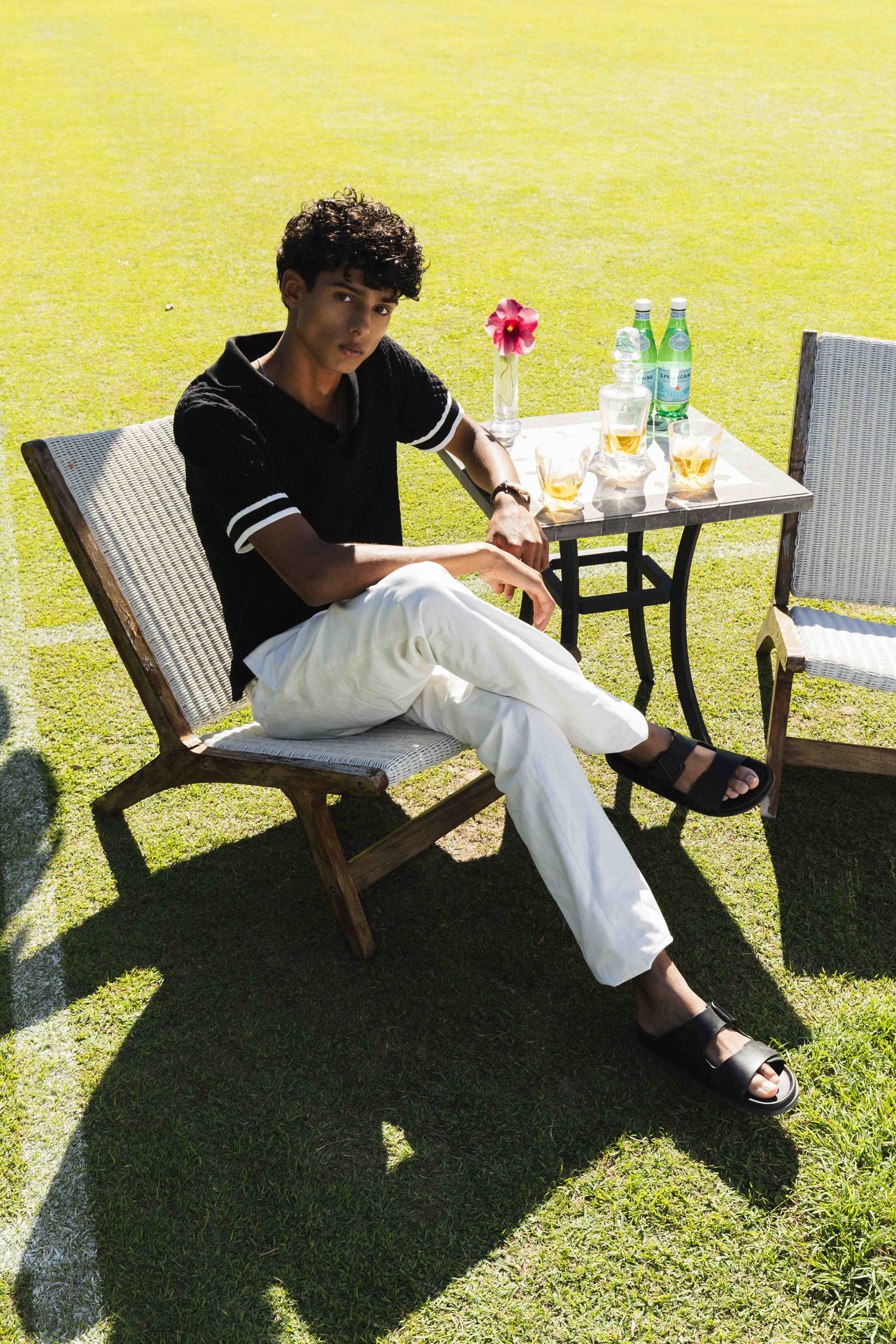 Person sitting on a chair outdoors with a table and drinks in the background