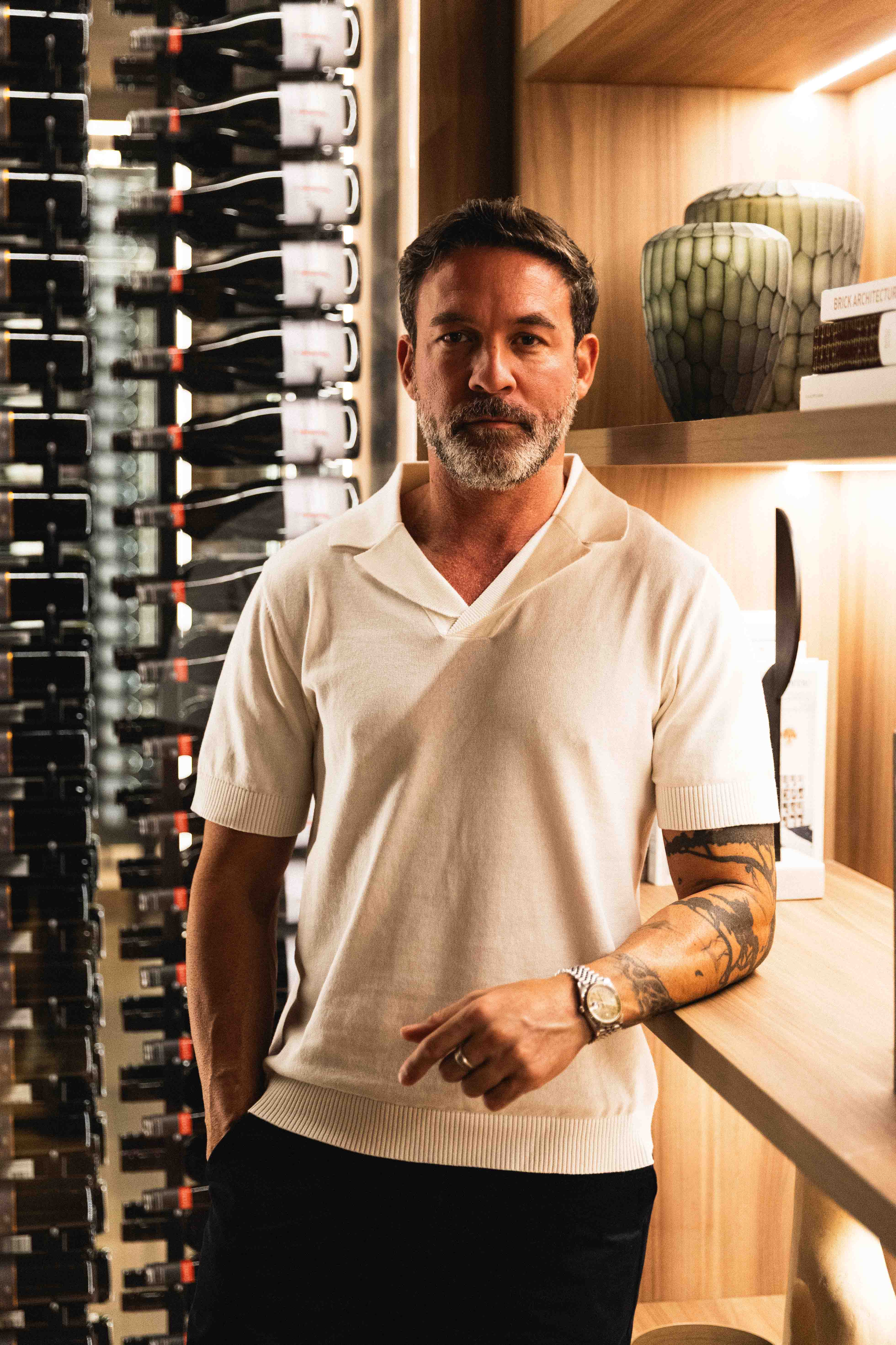 Man standing in a wine cellar with shelves of wine bottles.