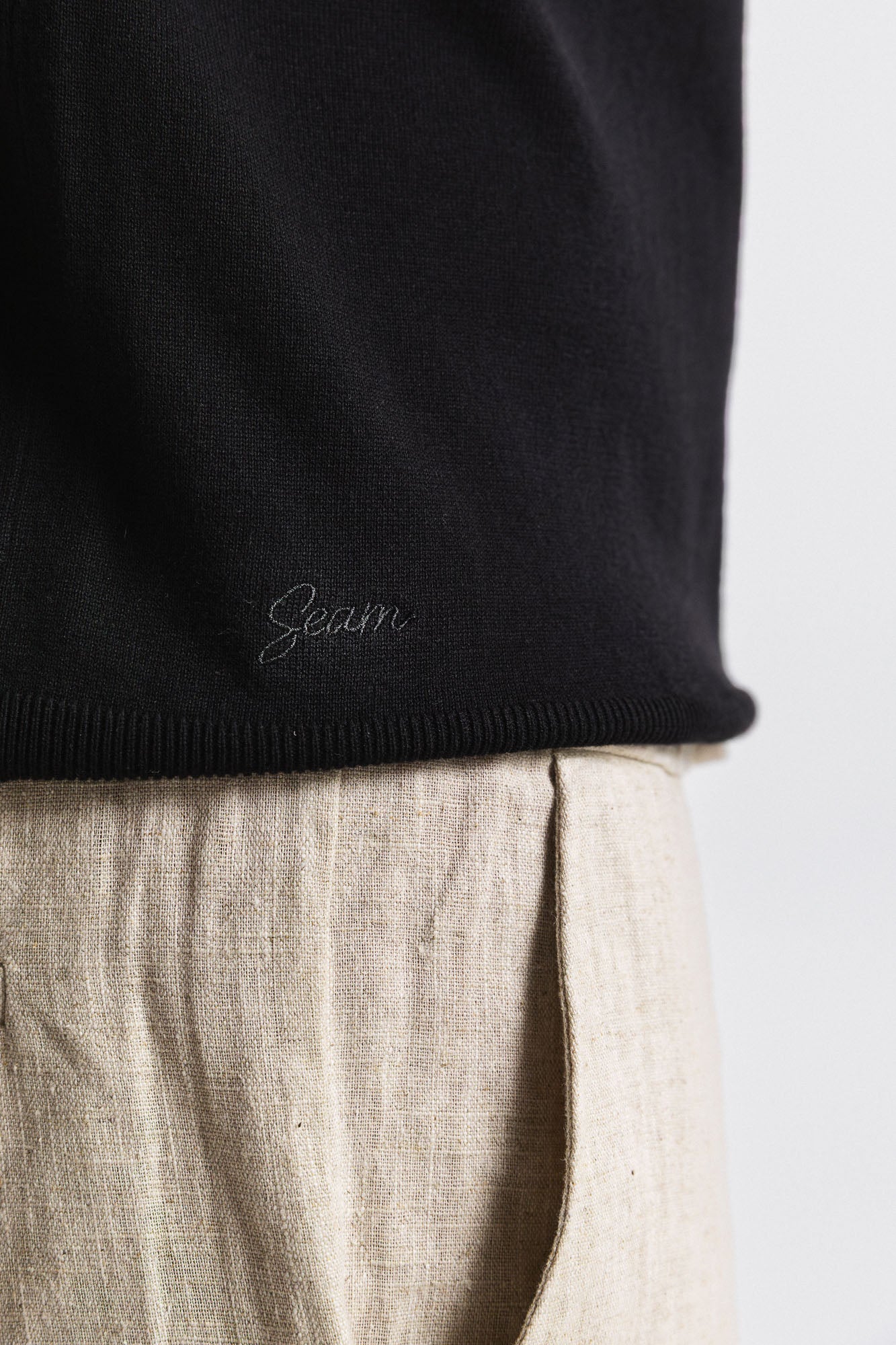 SEAM Cotton Knit Open Neck Polo in Black, close-up of Seam branding at collar