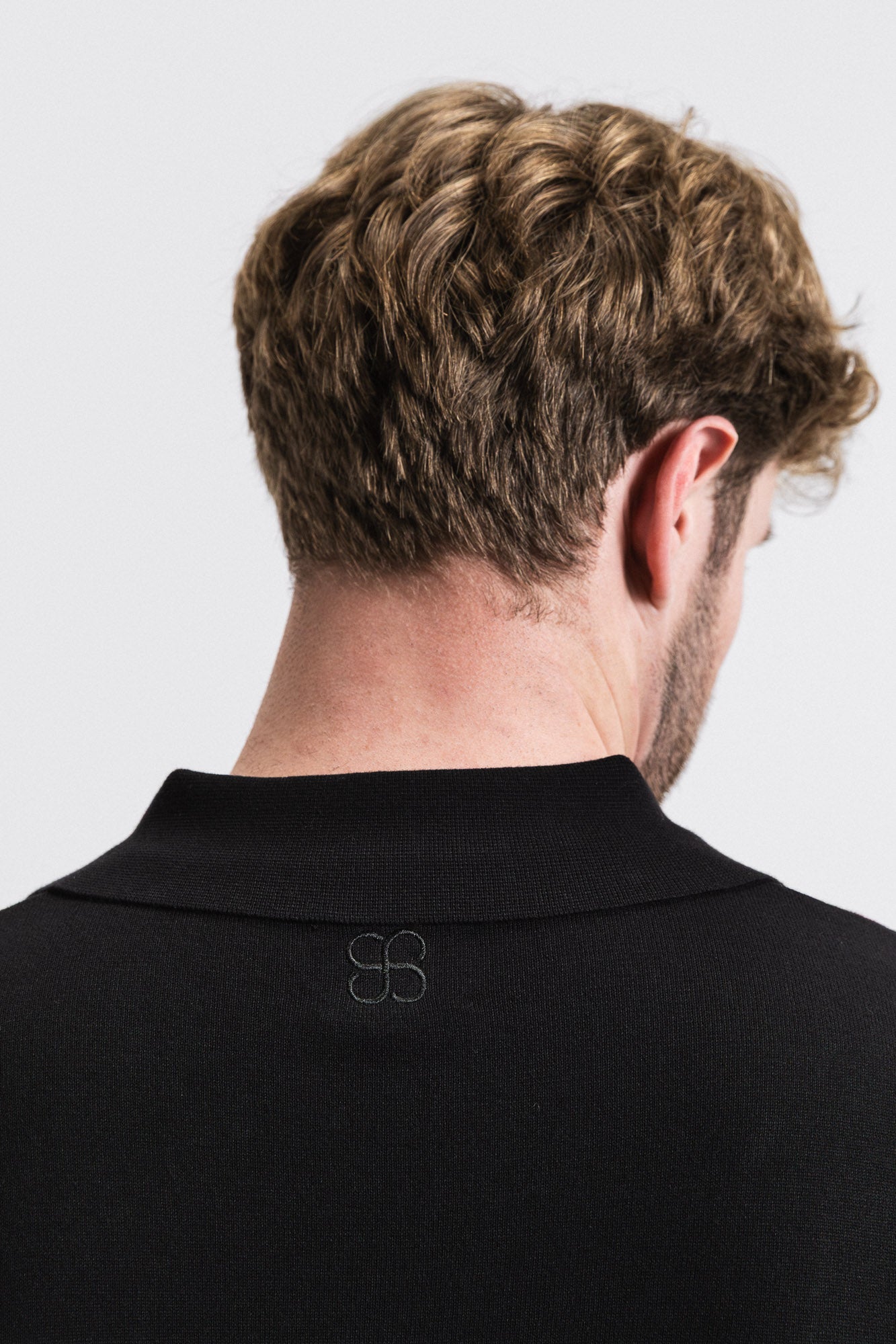 SEAM Cotton Knit Open Neck Polo in Black, back view showing embroidered logo