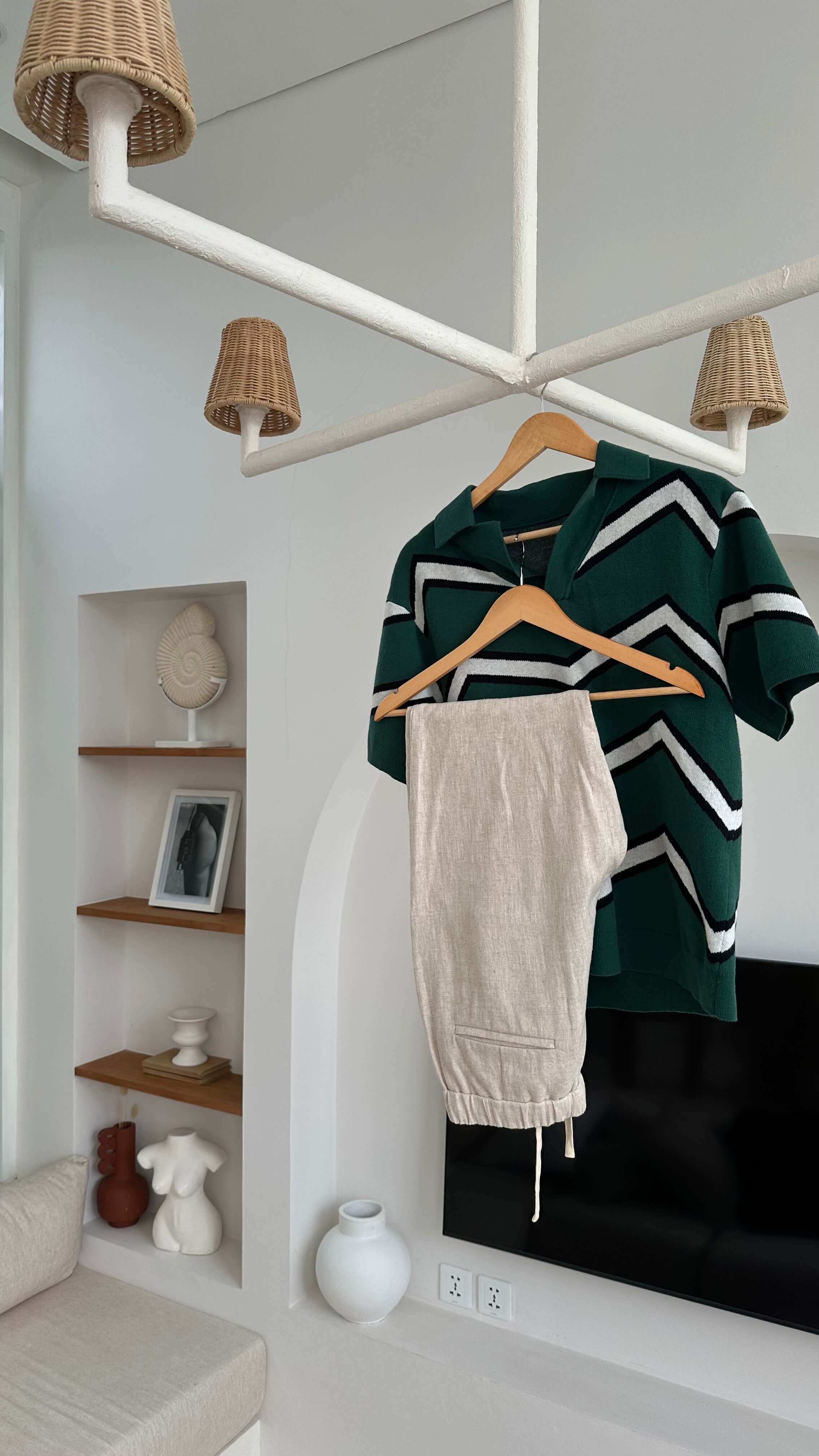 Green and white striped sweater on a hanger with a beige towel, in a room with shelves and decor.