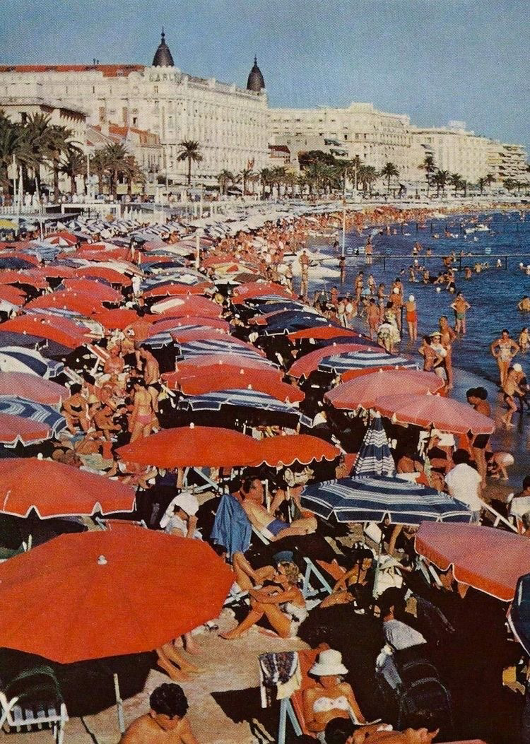 crowded beach with people and umbrellas by a large building
