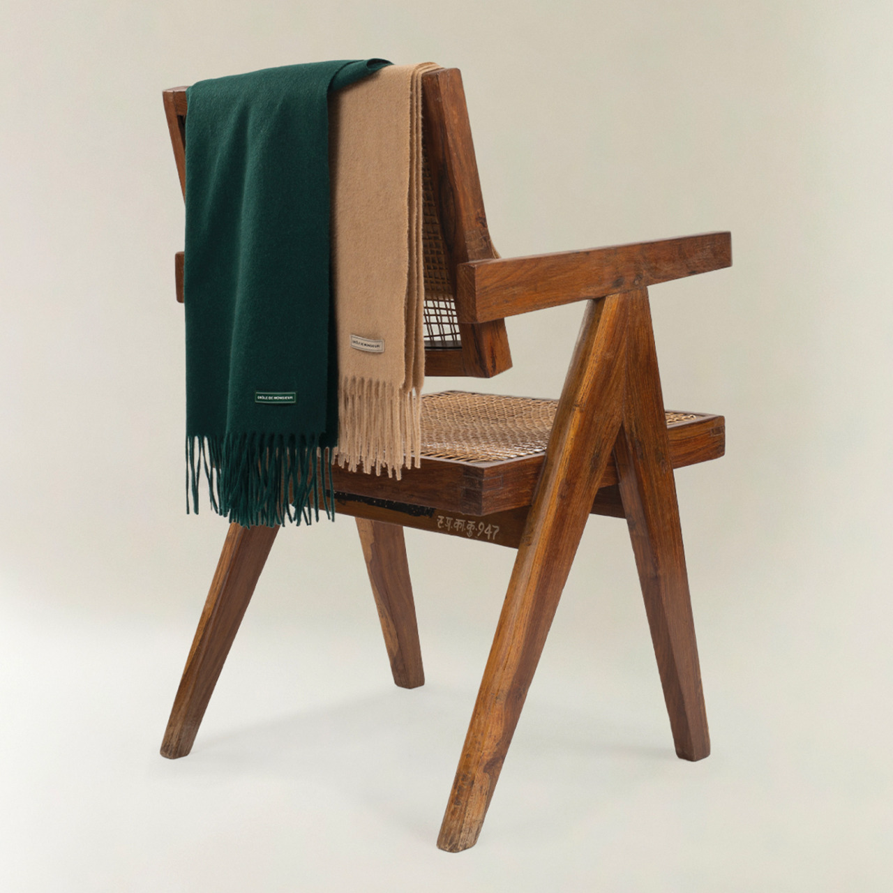 Wooden chair with two scarves draped over it on a plain background