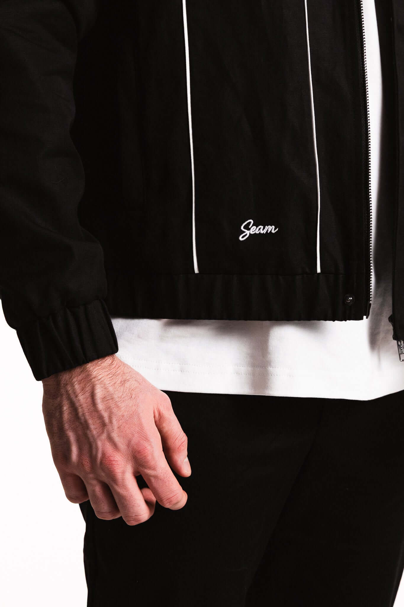 Close-up of a man wearing a Cotton Contrast Jacket featuring SEAM branding and contrasting white piping.