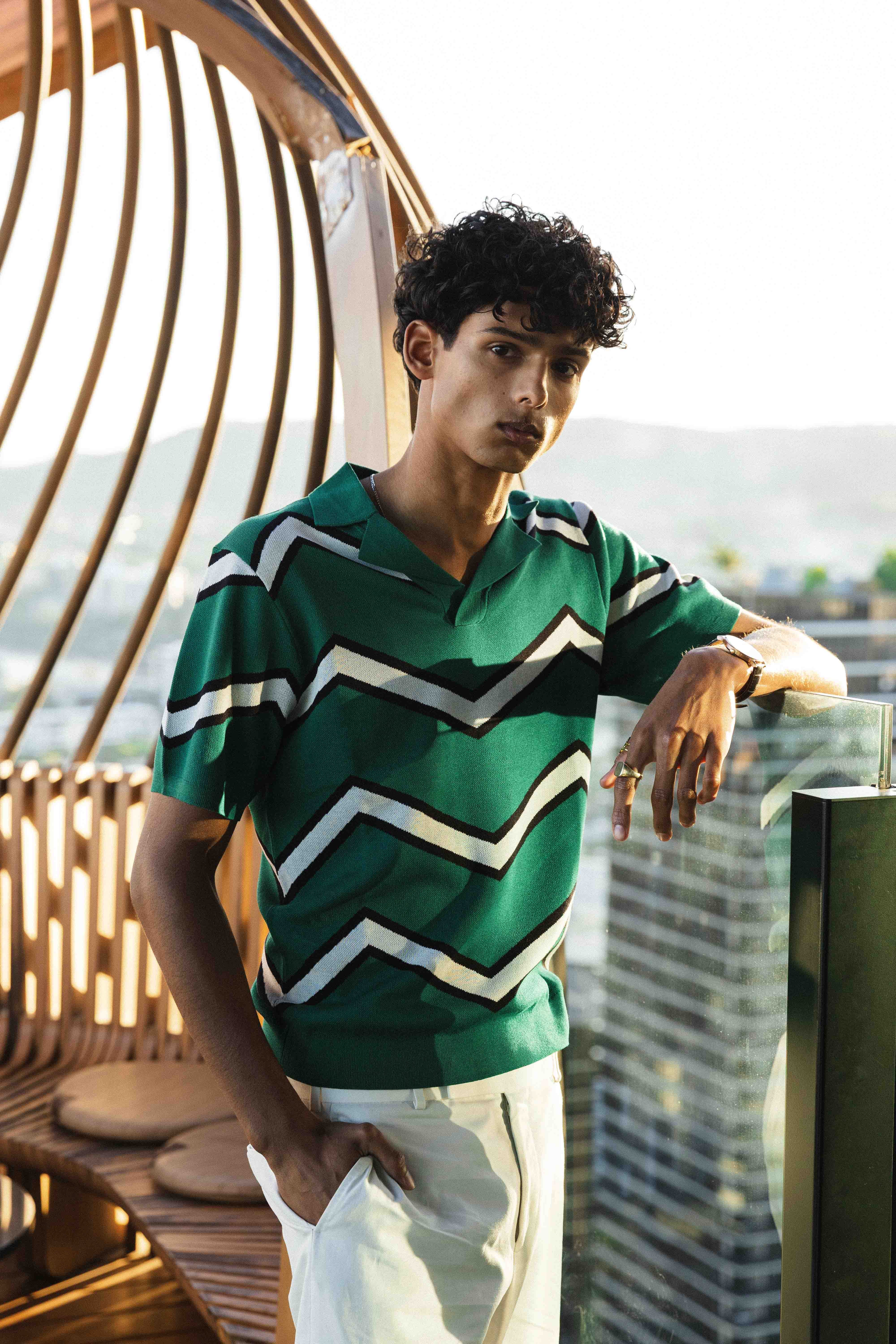 Man wearing a green and white striped shirt on a balcony