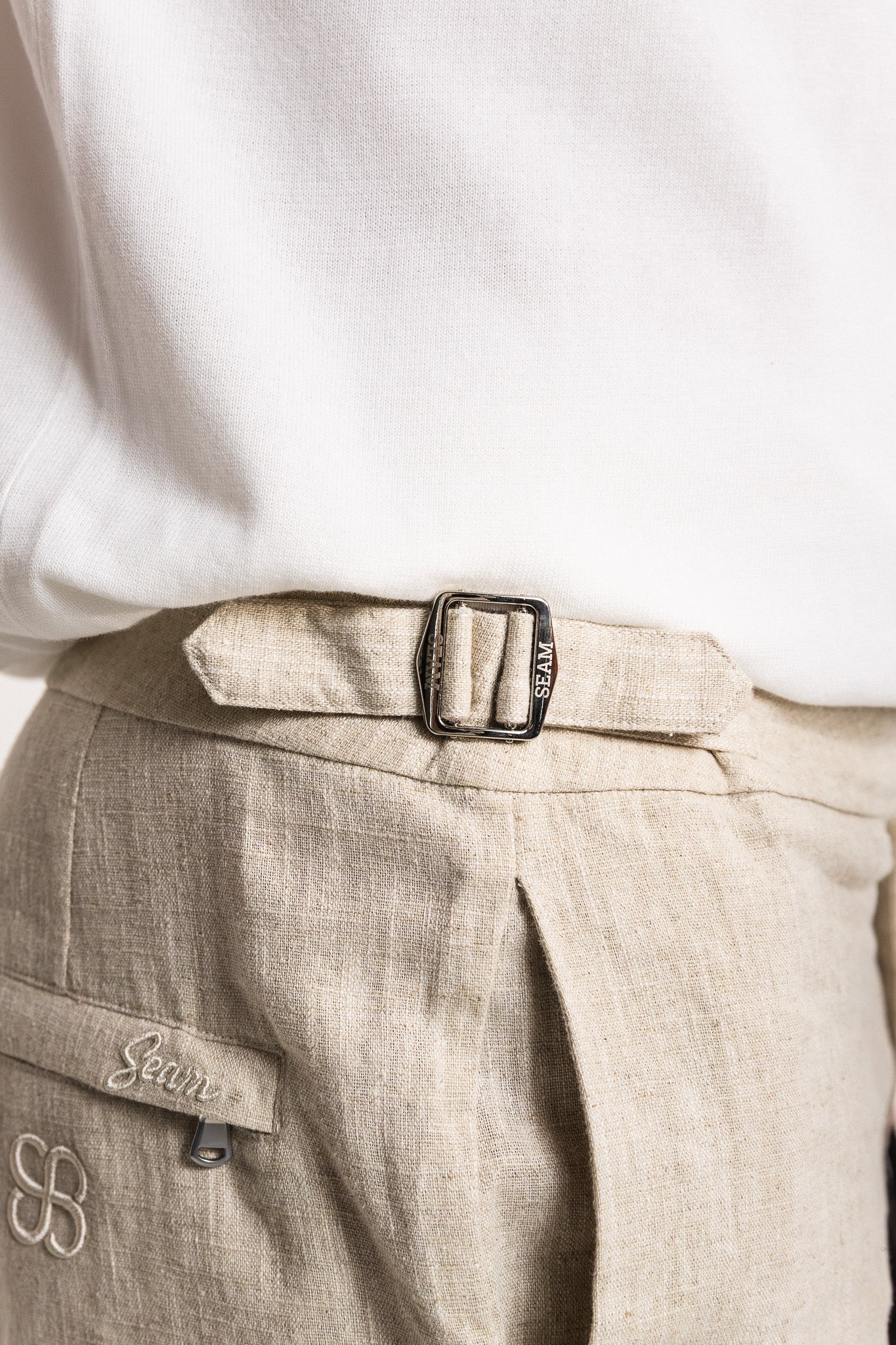 SEAM Side Tab Linen Short in Wheat, close-up of adjustable side tab and embroidered logo