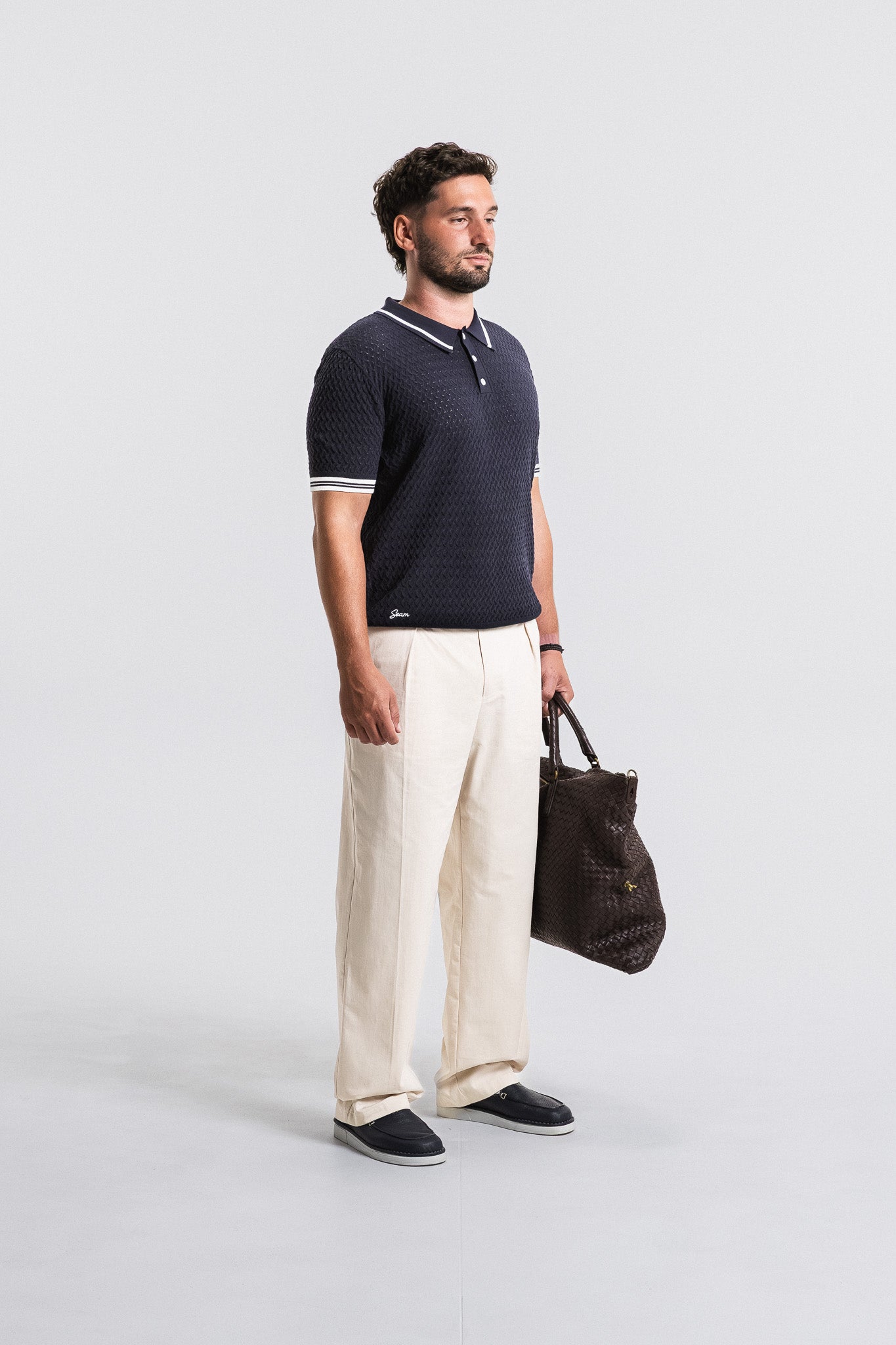 SEAM Poplin Pleated Trouser in Wheat, model styled with dark polo and bag