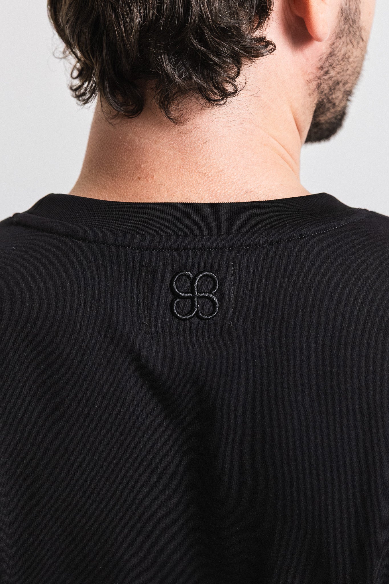 SEAM Relaxed Fit Cotton T-Shirt in Black, back view showing embroidered monogram