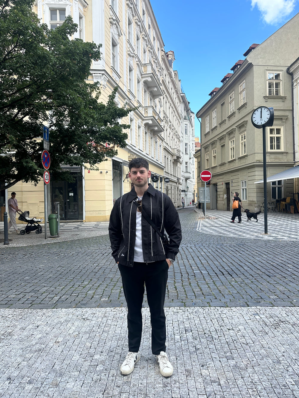 Person standing on a street with buildings and a clock in the background