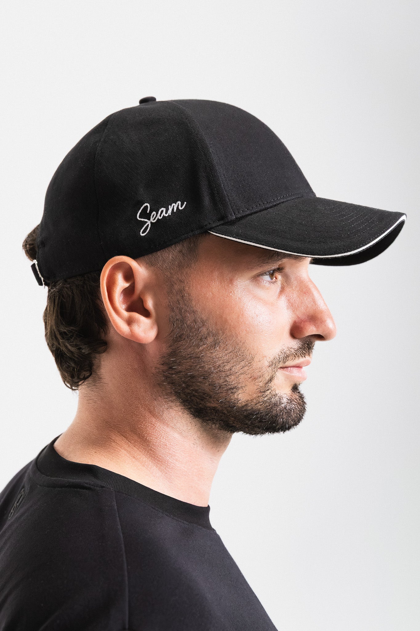 Man wearing a black cap with 'Gean' logo on a white background