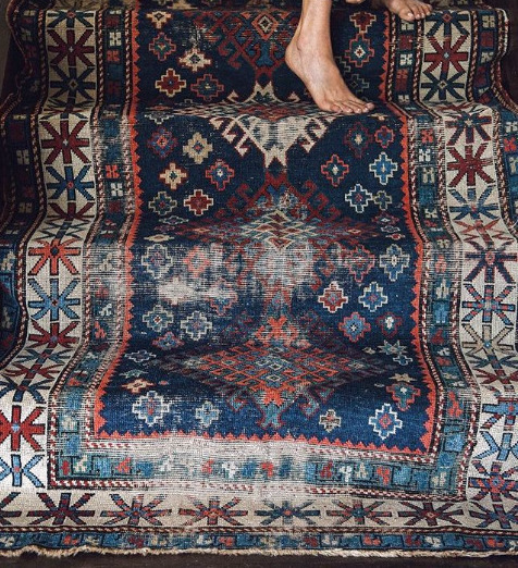 Close-up of a patterned rug with a person's foot stepping onto it